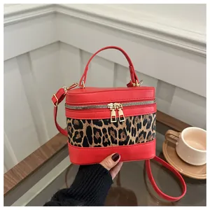 Detail view of red faux leather handbag featuring leopard print panel and dual zippers