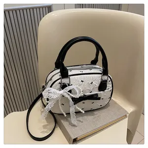 Detail of a white ruffled bowling bag with black bow patterns and pearl chain accents