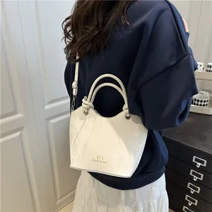 Minimalist white textured bucket bag with gold logo shown in a lifestyle indoor setting