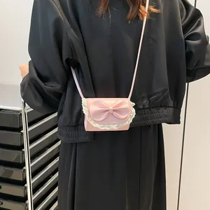 Mini pink crossbody bag with lace trim and large bow detail shown on a model