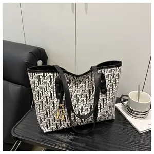 Close-up of the letter print tote bag with gold metal R pendant and black handles