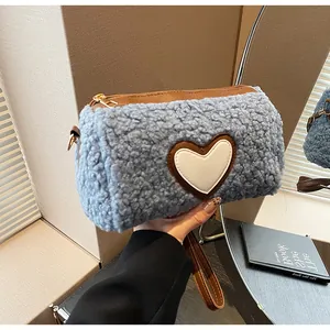 Detail of light blue fuzzy fleece cylinder bag with a heart patch and brown leather trim
