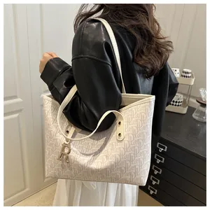 Detail view of monogram tote bag with gold R-shaped pendant and slim shoulder straps