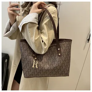 Detail of vintage patterned tote bag with luxury gold R-letter metal pendant charm