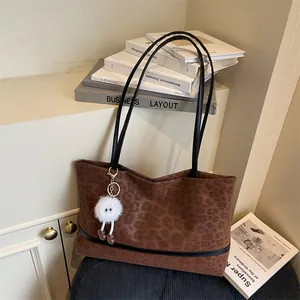 Vintage-Tasche mit Leopardenmuster, schwarzen Riemen und einem süßen Plüsch-Monster-Anhänger