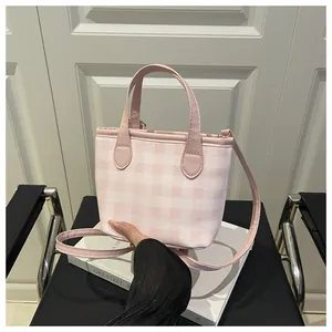 Detail of pink gingham canvas tote bag with leather handles on a white book prop
