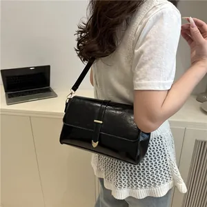 Sac bandoulière noir brillant minimaliste avec boucle coeur dorée et lanière décorative