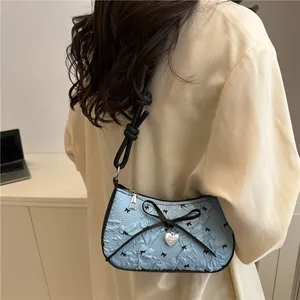 Borsa sottobraccio azzurra in seersucker con fiocchi neri e ciondolo a cuore argento