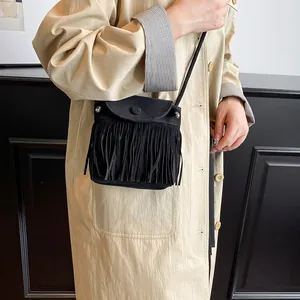Minimalistische schwarze Wildleder-Umhängetasche mit Fransen getragen zu einem Trenchcoat