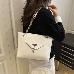 White faux leather tote bag with gold deer pendant and chain strap on shoulder