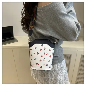 Detail of cherry print bucket bag with vibrant geometric pattern shoulder strap on model