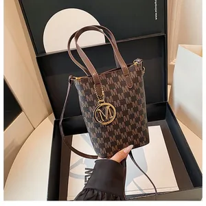 Sac seau vintage marron à monogramme avec pendentif M doré dans une boîte cadeau de luxe