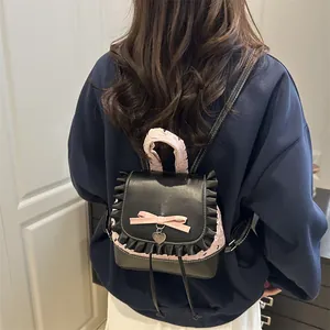 Mini sac à dos balletcore en cuir noir avec nœud rose et détails volantés sur modèle