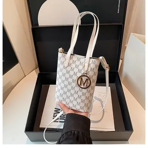 Détail du mini sac à main monogramme avec pendentif doré M en emballage cadeau chic