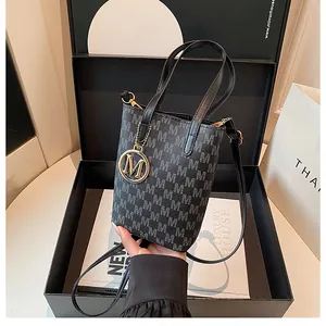 Détail du sac seau monogramme gris avec pendentif M doré et bandoulière noire
