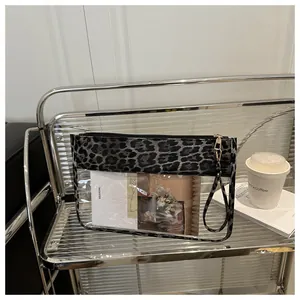 Detail of transparent PVC makeup bag with leopard print trim and portable hand strap