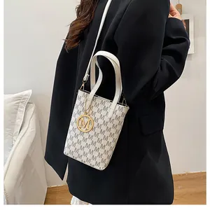 Détail du sac à main beige vintage avec motif monogramme et pendentif doré en métal