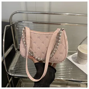 Detail of pink quilted hobo bag with bow embroidery and elegant pearl chain strap