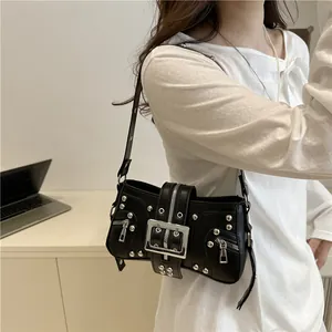 Punk style black shoulder bag with silver studs and metal buckle detail on office desk