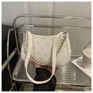 Close-up of white quilted leather bag with butterfly embroidery and pearl chain detail
