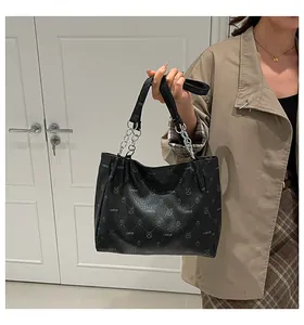Detail of black faux leather tote bag with rabbit print and silver chain handle