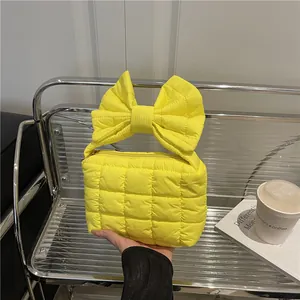 Bright yellow quilted handbag with oversized bow handle and puffy square texture