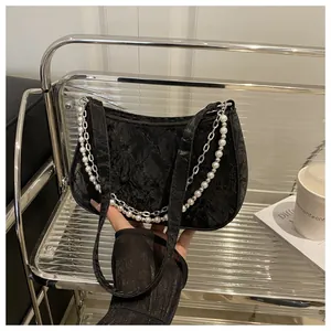 Detail of black pleated quilted baguette bag with pearl and metal chain straps