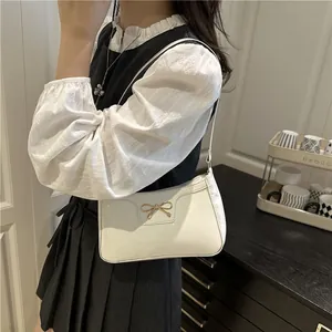 White faux leather shoulder bag with gold bow accent for elegant women's fashion