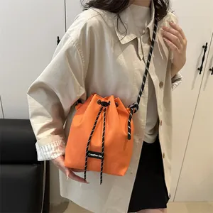 Borsa a secchiello in nylon arancione brillante con tracolla intrecciata bianca e nera