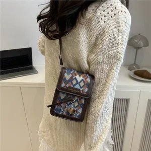 Retro geometric jacquard crossbody phone bag with leather trim on a wooden desk