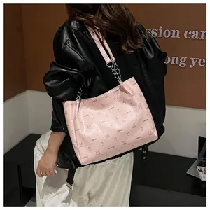 Pink printed PU leather tote bag with chain strap shown from a side view on a model