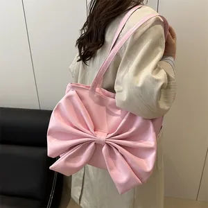 Chic pink tote bag with oversized bow detail worn by a model for a trendy autumn look