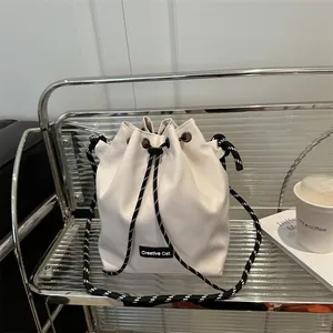 Borsa a secchiello in tela crema minimalista con tracolla in corda bianca e nera
