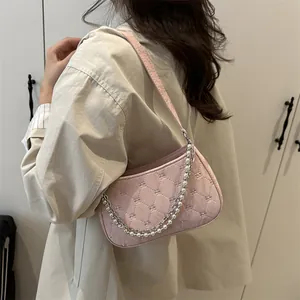 Pink quilted shoulder bag with decorative pearl and silver chain straps on model