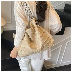 Detail of beige canvas tote bag featuring layered frayed fringe and woven shoulder strap