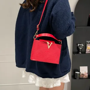 Sac à main carré en cuir tressé rouge avec boucle dorée en V porté en bandoulière