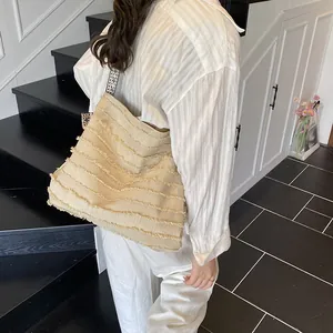 Beige canvas tote bag with fringed texture and woven strap shown in a casual side view