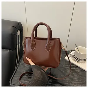 Detail of a dark brown vintage small square bag featuring glossy finish and round handles