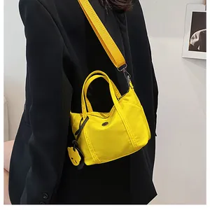 Detail of a vibrant yellow crossbody bag with a cute charm on a black blazer