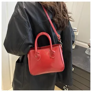 Detail of glossy red mini bag with gold hardware and adjustable shoulder strap