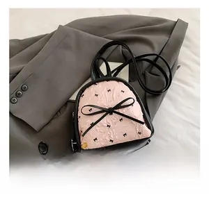 Detail showing pink pleated fabric with black bow prints on a mini backpack design