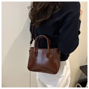 Detail view of glossy dark brown retro leather handbag worn as a stylish crossbody bag