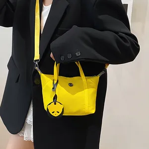 Mini yellow nylon tote bag with panda charm and shoulder strap on black blazer model