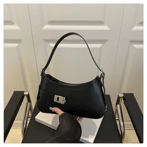 Détail d'un sac sous le bras en cuir noir avec boucle en métal argenté et coutures précises