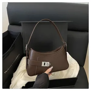 Détail d'un sac demi-lune marron foncé dans sa boîte avec fermoir métallique argenté