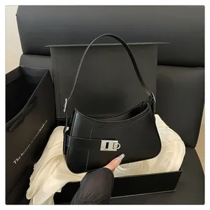 Détail du sac demi-lune en cuir noir avec boucle argentée et emballage cadeau de luxe