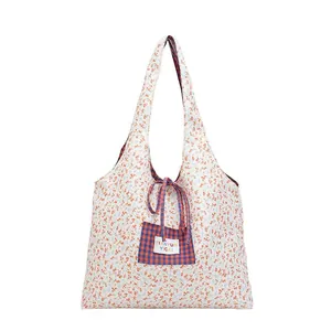 Floral reversible tote bag with a white floral pattern and a plaid pocket detail
