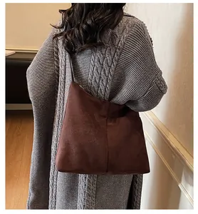 Détail du cabas en daim marron foncé avec couture décorative verticale et fermeture éclair