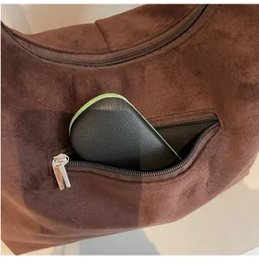 Détail de la poche zippée avant sur un sac hobo en daim marron pour le rangement