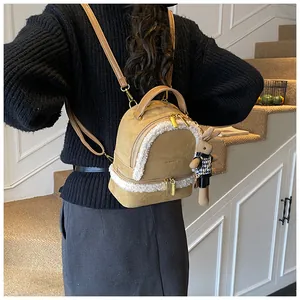 Detailansicht eines khakifarbenen Rucksacks mit weißem Kunstfellbesatz und Hasenanhänger